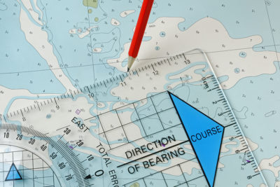 A course being plotted on an old chart with a pencil and course plotter